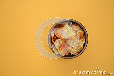Potato chips, crisp unhealthy chips, junk food, fast food concept. Potato chips in a bowl over bright yellow background. Stock Photo