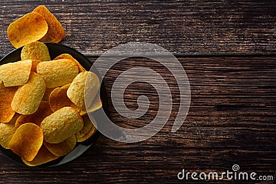 Potato chips over wooden background. Salty crispy snack. Copy space Stock Photo