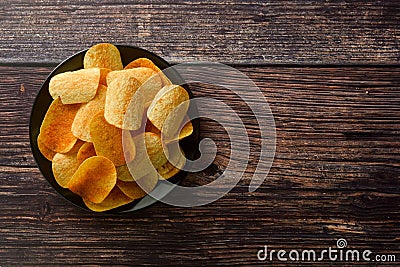 Potato chips over wooden background. Salty crispy snack. Copy space Stock Photo