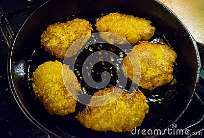 Potato pancakes, draniki, hash browns or fritters frying in old cast iron pan, skillet, selective focus Stock Photo