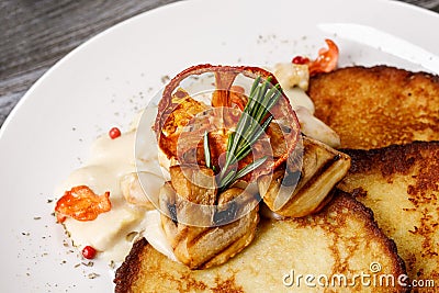 Potato pancakes with mushrooms and tomato on a white plate Stock Photo