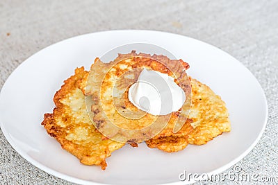 Potato pancakes raggmunk draniki deruny latkes or boxties on white plate. Polish placki ziemniaczane with sour cream Stock Photo