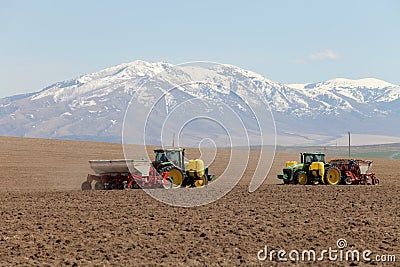 Two farmers in tractors planting potatoes. Stock Photo