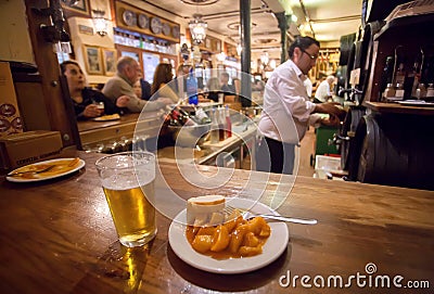 Potato tapas on plate and glass of beer for customer of busy fast-food restaurant in traditional spanish style Editorial Stock Photo