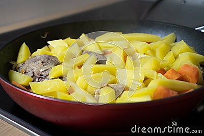 Potatoes, carrots and chicken were baked in a black pan Stock Photo