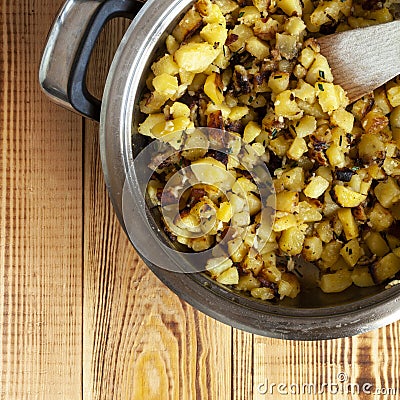 Potatoes fried with garlic and herbs, served in a apen, wooden background Stock Photo