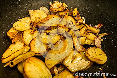 Potatoes fried in oil in a frying pan with herbs for autrian food Stock Photo