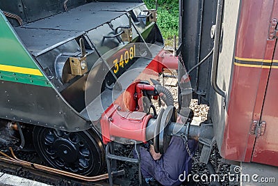 Famous British Steam Locomotive seen with its driver, with the driver cooling up a passenger railway carriage. Editorial Stock Photo