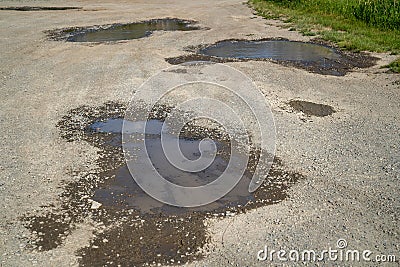 Potholes on a gravel dirt road, filled with water Stock Photo