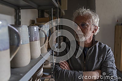 Potter craftsman in his studio showing the works displayed on a shelf Stock Photo