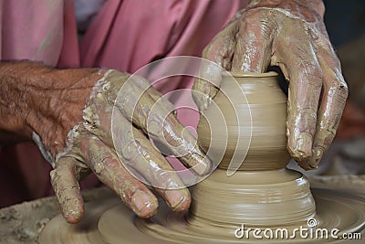 Potter creating pot on pottery wheel using clay Stock Photo