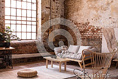 Pouf and wooden table on carpet near window in wabi sabi interior with sofa and armchair Stock Photo