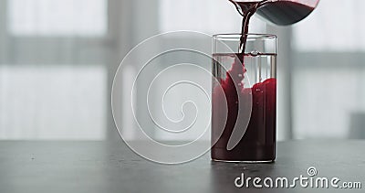 Pour blueberry juice in water in beaker glass on concrete countertop with window on a background Stock Photo