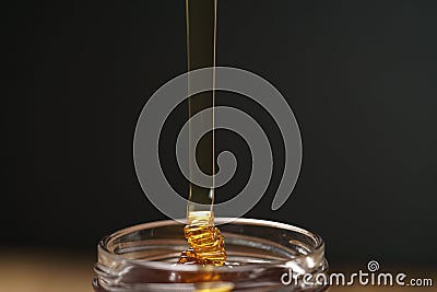 Pour honey into glass jar closeup Stock Photo