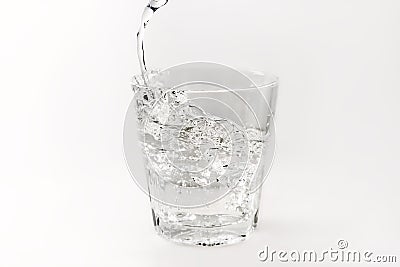 Pour water into a glass with splashes on a white background Stock Photo