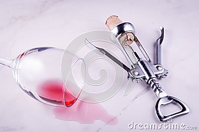 poured wine glass and corkscrew on marble background/ poured red wine glass and corkscrew on marble background. Top view Stock Photo