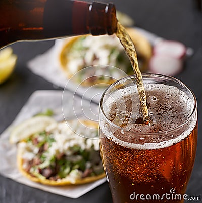 Pouring beer in front of mexican tacos Stock Photo