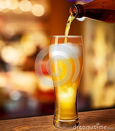 Pouring beer in glass on bar desk Stock Photo