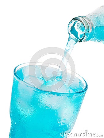 Pouring blue soda into glass with ice from bottle Stock Photo