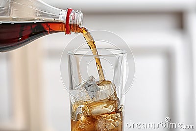 Pouring cola from bottle into glass on blurred background Stock Photo