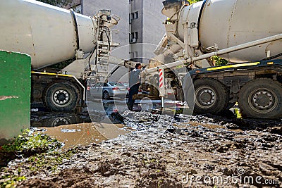 Concrete mixer at the construction site, pouring concrete from one mixer to other with pump for concrete Stock Photo