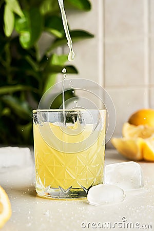 Pouring Italian typical digestive limoncello in a glass with kitchen background Stock Photo