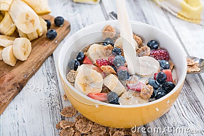 Pouring Milk in a bowl with Cornflakes and Fruits Stock Photo