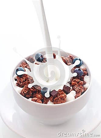 Pouring milk into chocolate cereal with berries Stock Photo