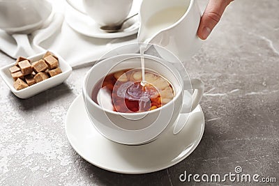 Pouring milk into cup of black tea Stock Photo