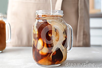 Pouring milk into mason jar with cold brew coffee Stock Photo