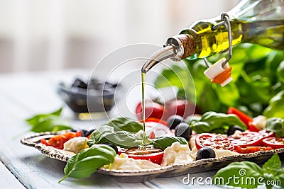 Pouring olive oil on caprese salad. Healthy italian or mediterranean meal Stock Photo