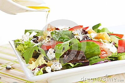 Pouring olive oil on fresh salad. Stock Photo