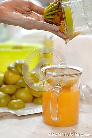 Pouring orange juice from a juicer into a glass jar. Stock Photo