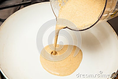 Pouring the quinoa crepes batter into a frying pan Stock Photo