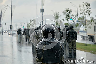 In the pouring rain, riot police in full tactical gear prepare to confront the protesters in the Belarus Editorial Stock Photo