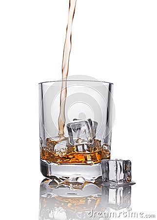 Pouring scotch whiskey in glass with ice cube Stock Photo