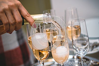 Pouring sparkling yellow champagne on wine glasses. Stock Photo