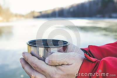 Pours hot tasty tea from a thermos in the winter into the cold. Stock Photo