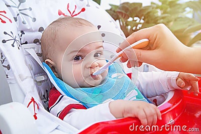 Pouting baby have lunch at the table in a suny day Stock Photo