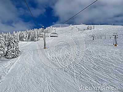 POV: Chairlift ride over vast ski resort slopes covered in pristine crud snow. Stock Photo