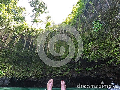 POV of feet floating in To Sua Trench swimming hole, Upolu Island, Western Samoa, South Pacific. Stock Photo