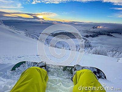 POV: Looking at sunset while sitting in fresh snow during a snowboarding trip Stock Photo