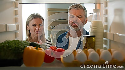 POV Point of view from inside fridge adult couple feeling bad disgusting unpleasant smell from broken refrigerator Stock Photo