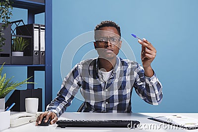 POV of unsure suspicious office administrator having pen in hand looking mistrustful at computer monitor. Stock Photo