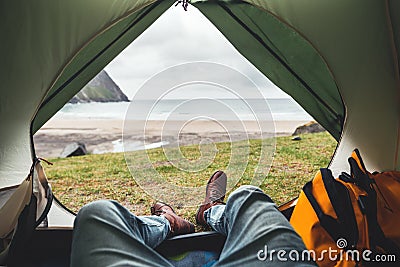 POV view of hipster tourist inside tent on front of mountains and sea Stock Photo
