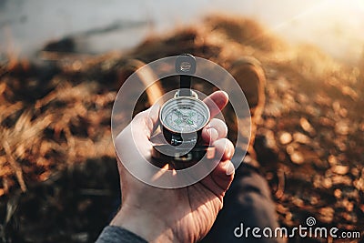 POV view of traveler hold compass in hand and legs in hiking boot. Blurred background Stock Photo