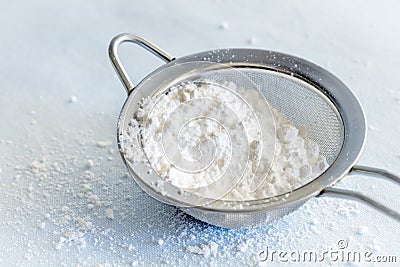 Powdered Confectioners Sugar in Sieve Closeup over Pastel Blue Stock Photo