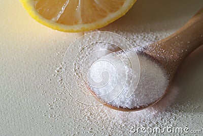 Powdered Vitamin C on wooden spoon with cut lemon on white background Stock Photo