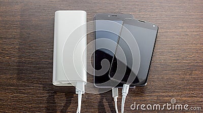 Power Bank charging two smartphones - dark wooden background Stock Photo