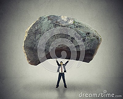 Power leadership ability to inspire man lifting up huge boulder Stock Photo